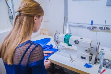 Atölyede dikiş makinesi kullanan profesyonel moda tasarımcısı.