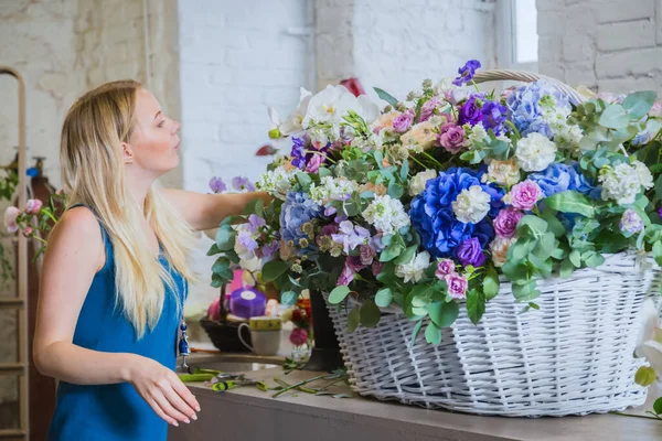 Florist making large floral basket with flowers at workshop, flower shop