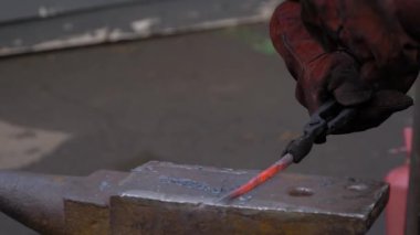 Demirci örste metalle çalışıyor. Ağır çekim, yakın çekim.