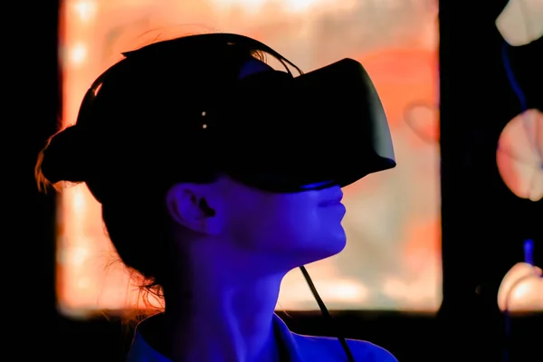 Young woman using virtual reality headset at dark interactive exhibition