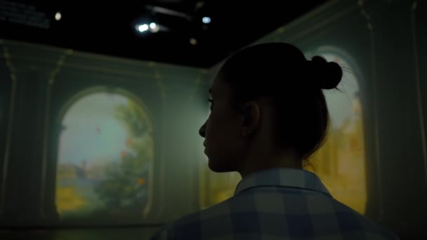 Молодая женщина смотрит вокруг на погружение выставки - видео-арт инсталляции — стоковое видео