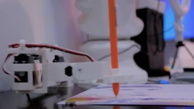 Robot fütüristik sergisinde portre çizen turuncu kalemli robot kol