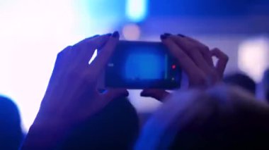 Kadın akıllı telefonlu canlı müzik konseri videosu kaydediyor.