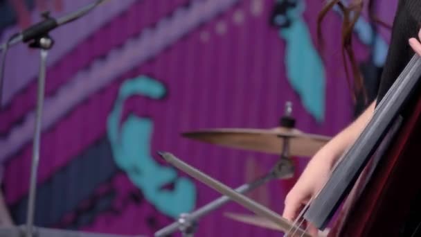 Slow motion: vrouwenhanden spelen elektrische cello op het podium van openluchtconcert — Stockvideo