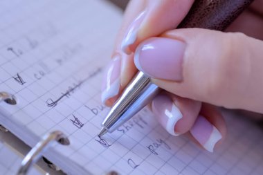 Defterde yapılacaklar listesine işaret koyan kadın - kapat