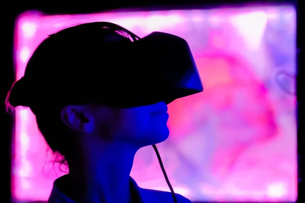 Young woman using virtual reality headset at dark interactive exhibition