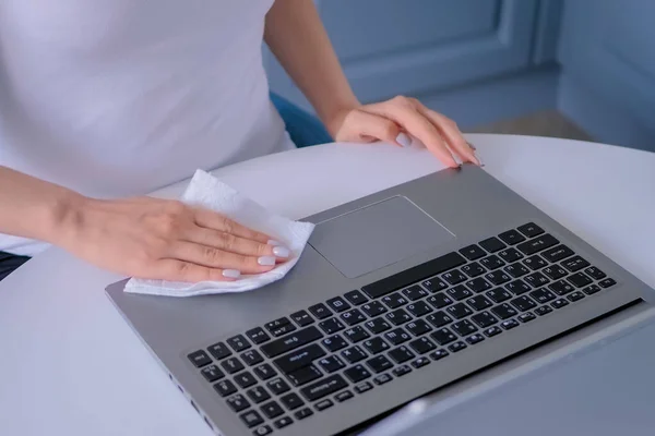 Woman hands cleaning laptop keyboard with wet wipe - close up