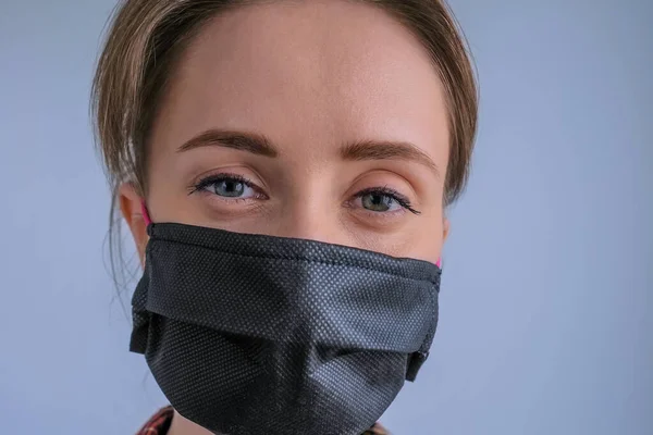 Woman wearing black medical face mask, looking at camera - quarantine concept