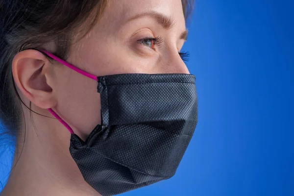 Woman wearing black medical face mask, looking away - quarantine concept
