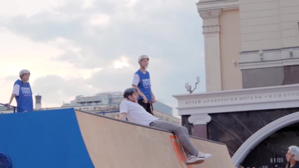 Teenage boy showing jump tricks over people on scooter at skatepark — Stock Video