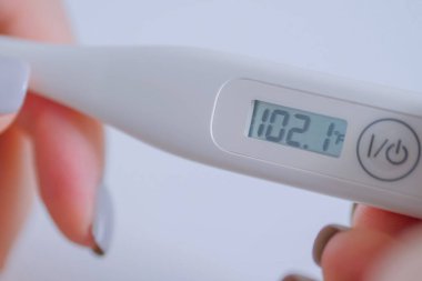 Yakın çekim: yüksek sıcaklıkta dijital medikal termometre tutan kadın