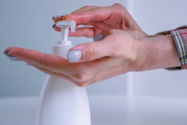 Kadın avuç içine antiseptik jel sıkıyor, ellerini temizliyor. Kapat.