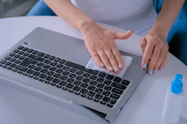 Woman hands cleaning laptop keyboard with wet wipe - close up