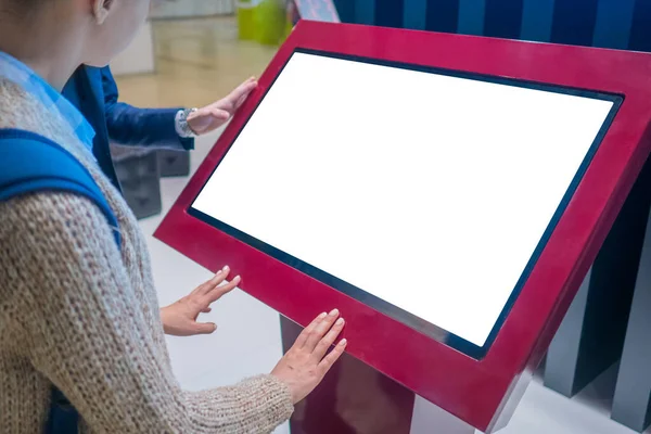 Woman using interactive empty white touchscreen display kiosk at exhibition