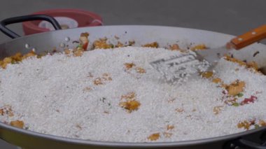 Yavaş çekim: Aşçı kızarmış tavuk, sebze, pilav ile paella pişiriyor. Yakın çekim.
