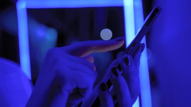 Sergide mavi ışıklandırmalı akıllı telefon kullanan kadın - yan görüntüyü kapat