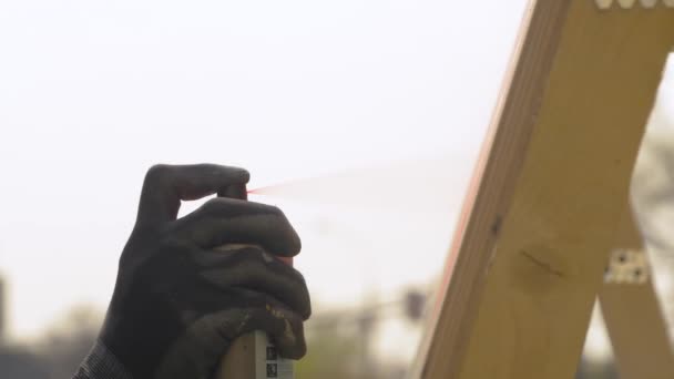 Slow motion: man spuiten verf uit blik op houten oppervlak op graffiti festival — Stockvideo