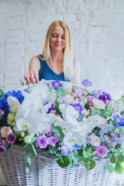 Florist making large floral basket with flowers at flower shop