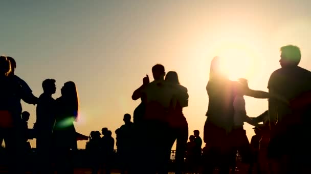 As pessoas silhuetas aprendem a dançar no cais da cidade ao pôr-do-sol - câmera lenta — Vídeo de Stock
