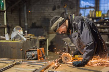 Demirci el testeresiyle metal kesiyor.