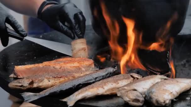 Cuoco cottura carne capesante, salmone, pesce profumato su braciere nero - primo piano — Video Stock