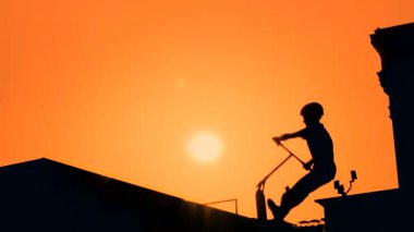 Yavaş çekim: Gün batımında motosiklette yüksek atlama numaraları gösteren genç silueti