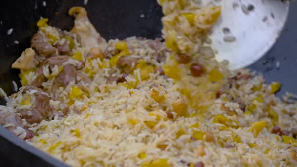 Movimento lento: chef cozinhar pilaf em caldeirão enorme no verão mercado de alimentos ao ar livre — Vídeo de Stock