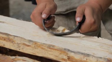 İnsan marangoz, tahta tahtayı şekillendirmek ve pürüzsüz hale getirmek için çakı kullanır. Yavaş çekim.