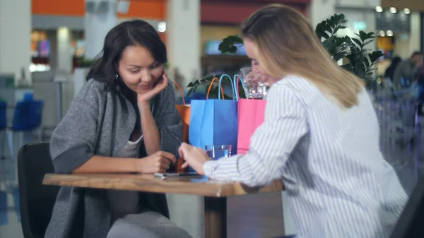 Dos mujeres que utilizan teléfonos inteligentes en la cafetería en el centro comercial — Foto de Stock
