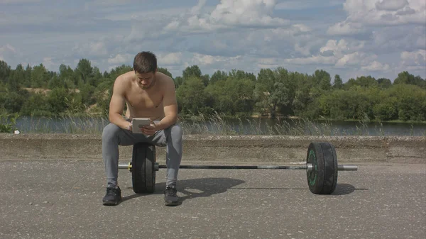 Joven deportista caucásico utilizando su tableta después de tren al aire libre — Foto de Stock