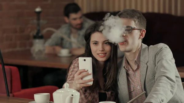 Элегантная пара курит кальян и делает селфи на смартфоне — стоковое фото