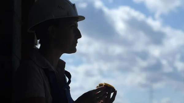 На будівельному майданчику жінка-працівник їсть смачний бутерброд під час робочого обіду Ліцензійні Стокові Фото