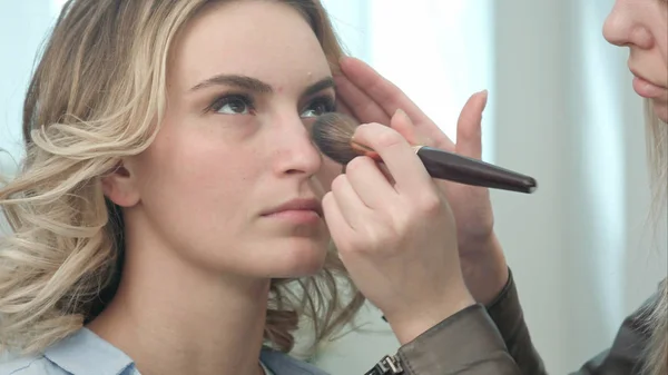 Professional make up artist applying powder to a young model face — Stock Photo, Image