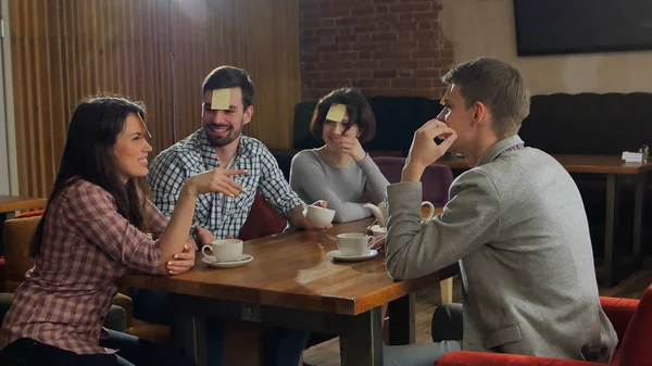 Cuatro amigos están jugando juntos quién soy en la cafetería — Foto de Stock