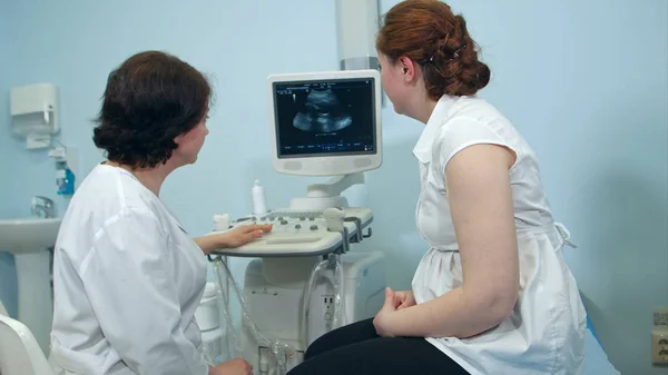 Женщина-врач показывает результаты ультразвука пациентке в клинике — стоковое фото