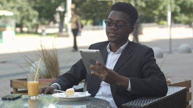 Yakışıklı afro Amerikalı adam tablet, dış kafede otururken kullanma