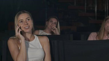 Genç kadın sinemada film sırasında telefonda