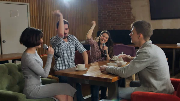 Amigos felizes cantando karaoke juntos em um bar — Fotografia de Stock