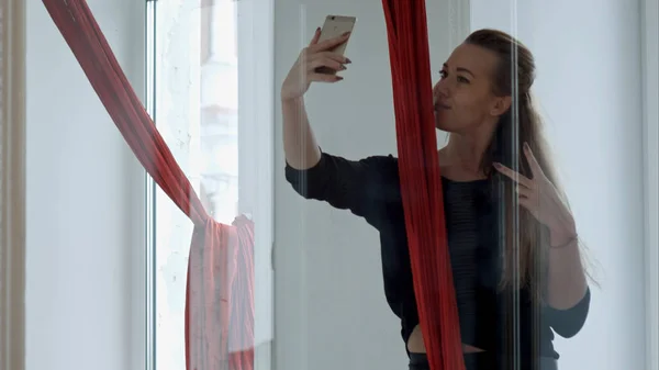 Hermosa bailarina tomando selfie usando smartphone con seda aérea después del entrenamiento — Foto de Stock