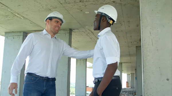 Empresário agitando as mãos com o construtor no local de construção — Fotografia de Stock