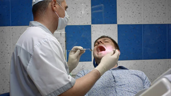 Jonge mannelijke patiënt repareren van tanden in tandheelkundige kliniek — Stockfoto