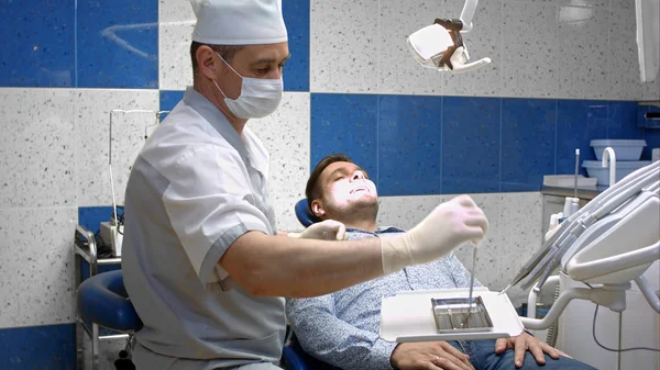 Fogorvos észleli a szuvas fogak, a páciens a fogorvos szék — Stock Fotó