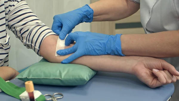 Enfermeira colocando gesso no braço feminino após doação de sangue — Fotografia de Stock