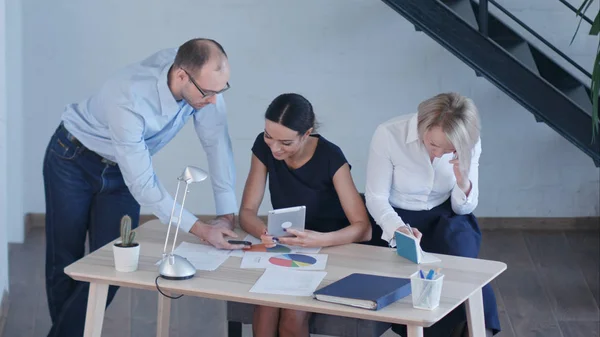 Grupo de jóvenes empresarios que trabajan y se comunican juntos en una oficina creativa, utilizando diferentes dispositivos — Foto de Stock