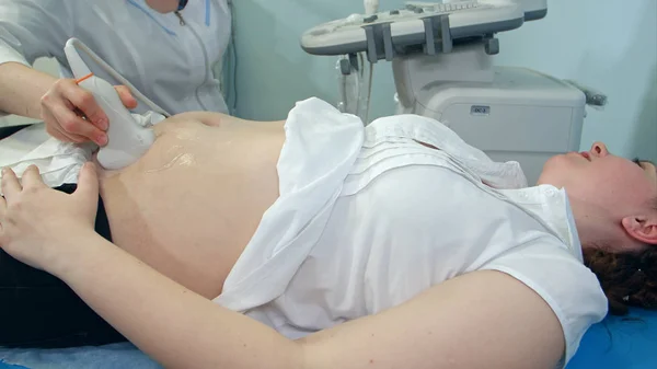 Kvinnliga läkare göra ultraljud på magen av gravid kvinna i klinik — Stockfoto