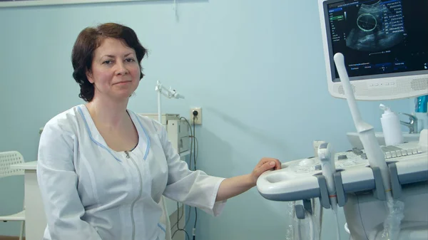Leende kvinna läkare sitter bredvid ultraljud diagnostik enhet — Stockfoto