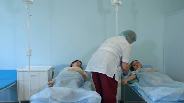 Bir hastane koğuşunda bir damla koyarak kadın hastanın hemşire