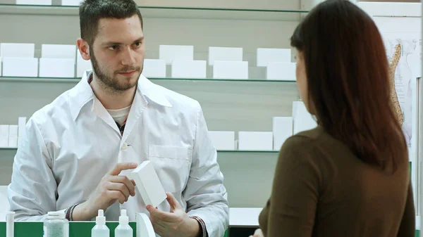 Farmacêutico masculino e cliente feminino na farmácia — Fotografia de Stock