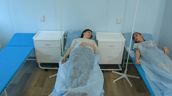 Två kvinnliga patienter ligga i sjukhussängar på dropp talar — Stockfoto