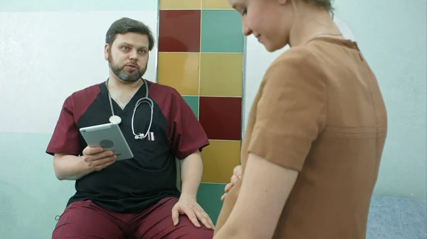 Heureux médecin ayant une cunsultation avec la femme enceinte, en utilisant une tablette numérique — Photo